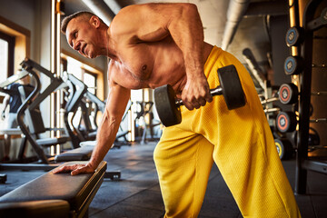 Fototapeta premium Hard-working male athlete doing physical exercises at gym