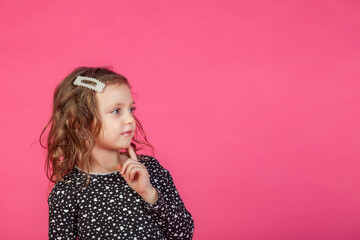 Obraz na płótnie Canvas Portrait 5-6 year old girl in dress on pink isolated background looks at camera. Concept Playing and Children Recreation. Little child in casual clothes posing and showing emotions. Copy space