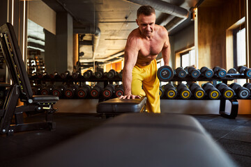 Fototapeta premium Serious sporty man doing his workout programme at the gym