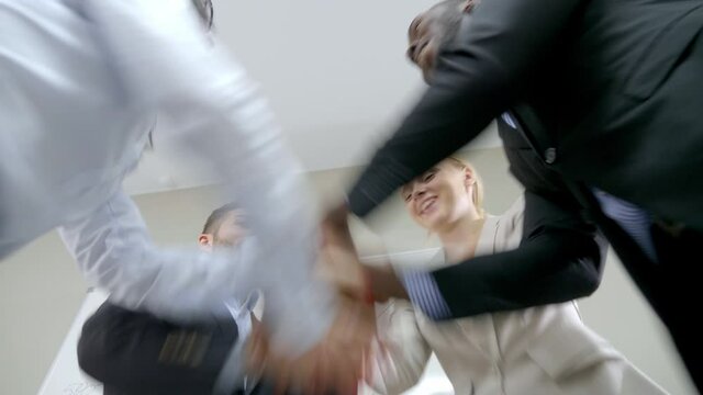 Group of happy colleagues forming hand stack in office.