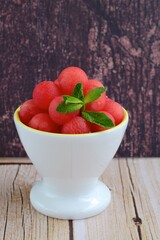 Watermelon balls in a bowl, garnish with mint leaf. 