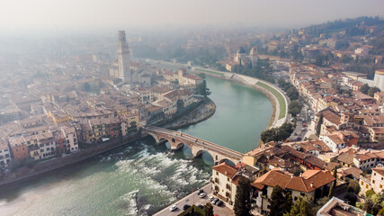 Aerial view of Verona crossed by the Adige river and shrouded in winter fog.