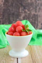 Watermelon balls in a bowl, garnish with mint leaf. 