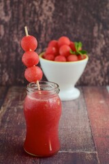 Watermelon juice with watermelon ball skewer on wooden background
