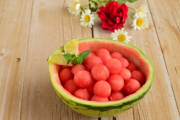 Fruit salad of watermelon balls in a watermelon skin bowl, daisy flower at the background