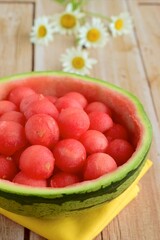 Fruit salad of watermelon balls in a watermelon skin bowl, daisy flower at the background
