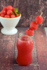 Watermelon juice with watermelon ball skewer on wooden background
