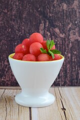 Watermelon balls in a bowl, garnish with mint leaf. 