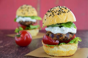 Vegetarian burger. Sesame bread bun with lentil patty, tomato, lettuce and yogurt