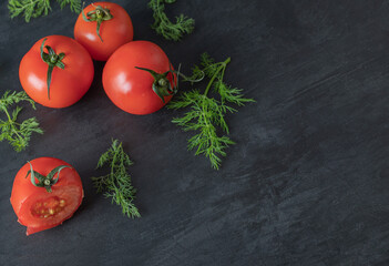 Fresh whole tomatoes with greens on a dark background