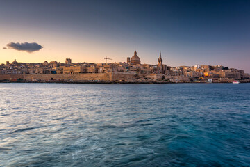 Fototapeta premium Rocky coastline of Malta and beautiful architecture of the Valletta city at dawn