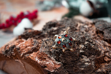 A brooch in the form of a turtle made of amber and bronze against a background of wooden texture close-up. 