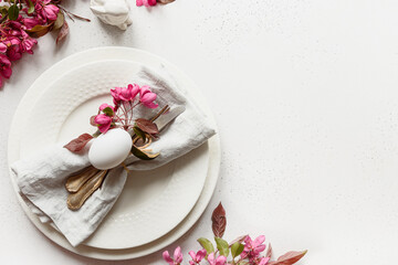 Festive Easter table setting with blooming apple flowers on white table. Top view. Copy space.