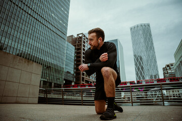 Caucasian male athlete kneeling preparing for run exercising in city