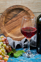 Bunch of grapes, a glass of red wine and a bottle of wine on blue 