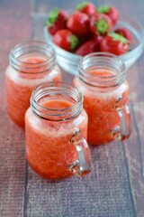 Fototapeta na wymiar Fresh organic strawberry juice in glass jar, selective focus