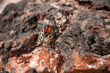 Ring in the form of a cicada of bronze and amber on the wooden bark of birch slice