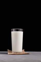 Ayran or kefir in glass. Fermented milk ayran. Milk diet for weight loss. Dark background, vertical orientation, copy space