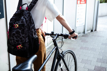 都心を自転車で移動する若いカジュアルなファッションの女性
