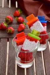 Homemade Vegan Strawberry Chia Coconut Milk Popsicles on wooden table. Summer dessert