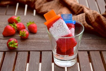 Homemade Vegan Strawberry Chia Coconut Milk Popsicles on wooden table. Summer dessert