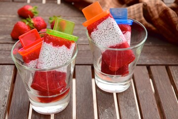 Homemade Vegan Strawberry Chia Coconut Milk Popsicles on wooden table. Summer dessert