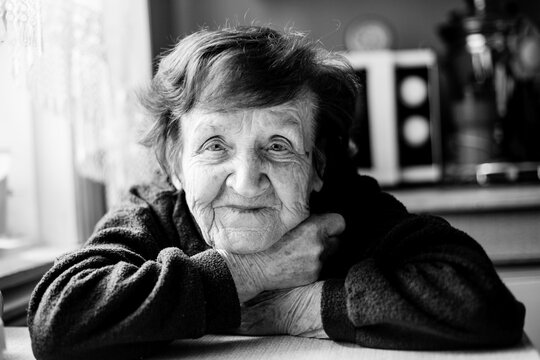 Portrait of an old woman in her home. Black and white photo.