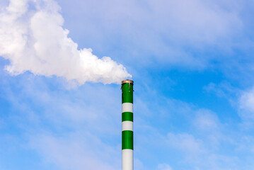 One Industrial smoke pipe from chimney on blue cloudy sky.