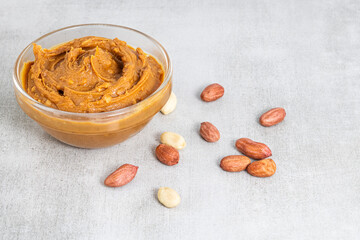 peanut butter and peanuts on gray background with copy space