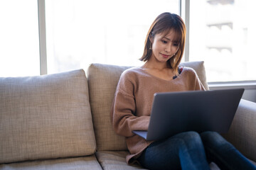 Naklejka premium リビングでパソコンを使う女性