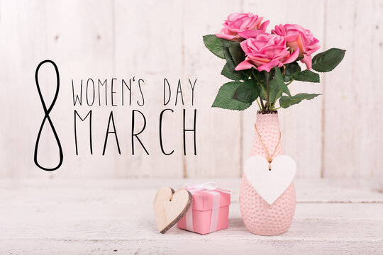 Abstract composition for Women's Day. Pink flower petals flying with hearts symbols, defocused background.