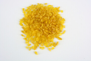 Fresh grains, cereals, yellow Bulgur scattered in plastic container and white background with interesting lighting. 