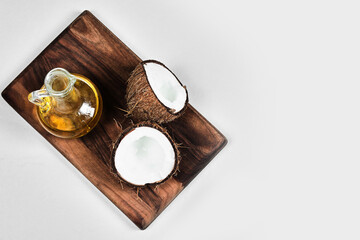 Half cut coconut and bottle of oil on the wooden board