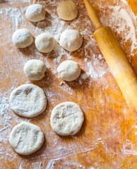 Balls and disks of dough, wooden rolling pin and wheat flour on a wooden cutting Board closeup