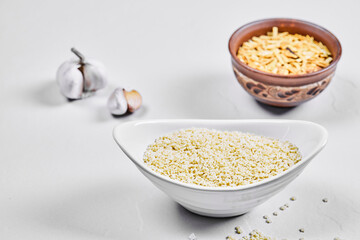 Two bowls of raw pastas with garlic on white background