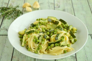 Pasta spaghetti with fresh peas, zucchini, thyme and parmesan cheese
