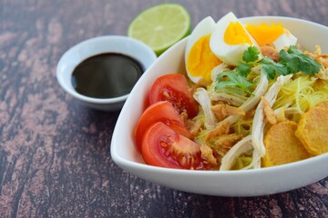 Soto Ayam, Indonesian food, yellow spicy chicken soup with vermicelli, fried potato, hard boiled egg and fried shallot.