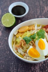 Soto Ayam, Indonesian food, yellow spicy chicken soup with vermicelli, fried potato, hard boiled egg and fried shallot.