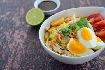 Soto Ayam, Indonesian food, yellow spicy chicken soup with vermicelli, fried potato, hard boiled egg and fried shallot.