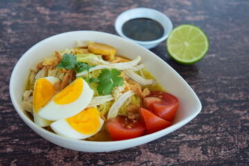 Soto Ayam, Indonesian food, yellow spicy chicken soup with vermicelli, fried potato, hard boiled egg and fried shallot.
