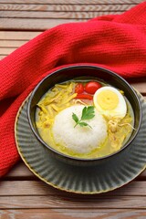 Soto Ayam, yellow spicy chicken soup with egg, tomato, bean sprouts and rice