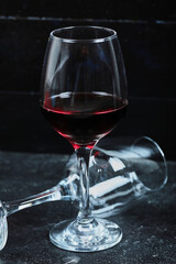 A glass of wine and empty glass on the dark background