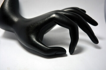 Ceramic, clay female hand covered with black matte paint is located on a white background. 