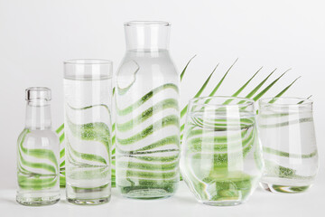 palm leaf distorted through water in glasses and bottles on white background. Home decor, eco friendly, pure water,gardening concept.Nature background