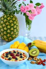 Mango banana pineapple smoothie bowl topped with raspberry, blueberry, goji berry and chia seeds