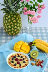 Mango banana pineapple smoothie bowl topped with raspberry, blueberry, goji berry and chia seeds