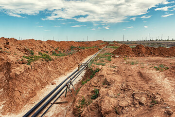 Metal technological pipelines in a trench in the middle of the steppe