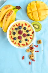 Gordijnen Mango banana pineapple smoothie bowl topped with raspberry, blueberry, goji berry and chia seeds. Top view © AmalliaEka