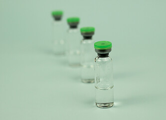 one vaccine in the foreground, the jars in the background in defocus. medical preparations. liquid substance in glass.