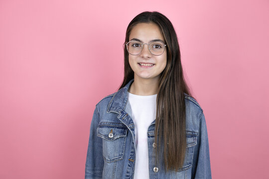 Beautiful child girl with long hair wearing a denim jacket standing over isolated pink background with a happy face standing and smiling with a confident smile showing teeth